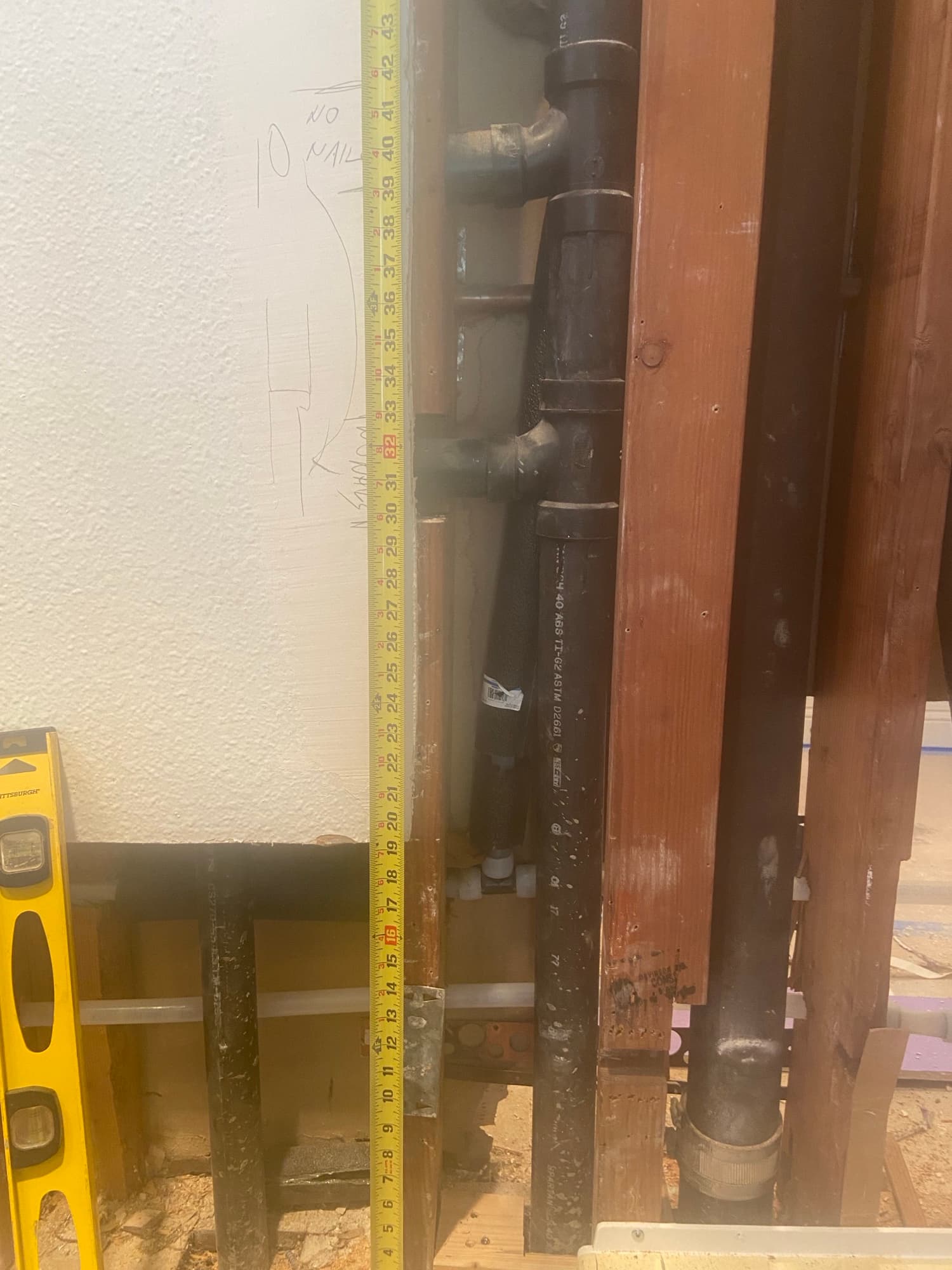 Tape measure checking pipe clearance on a Schedule 40 ABS drain tee, Orange County, CA
