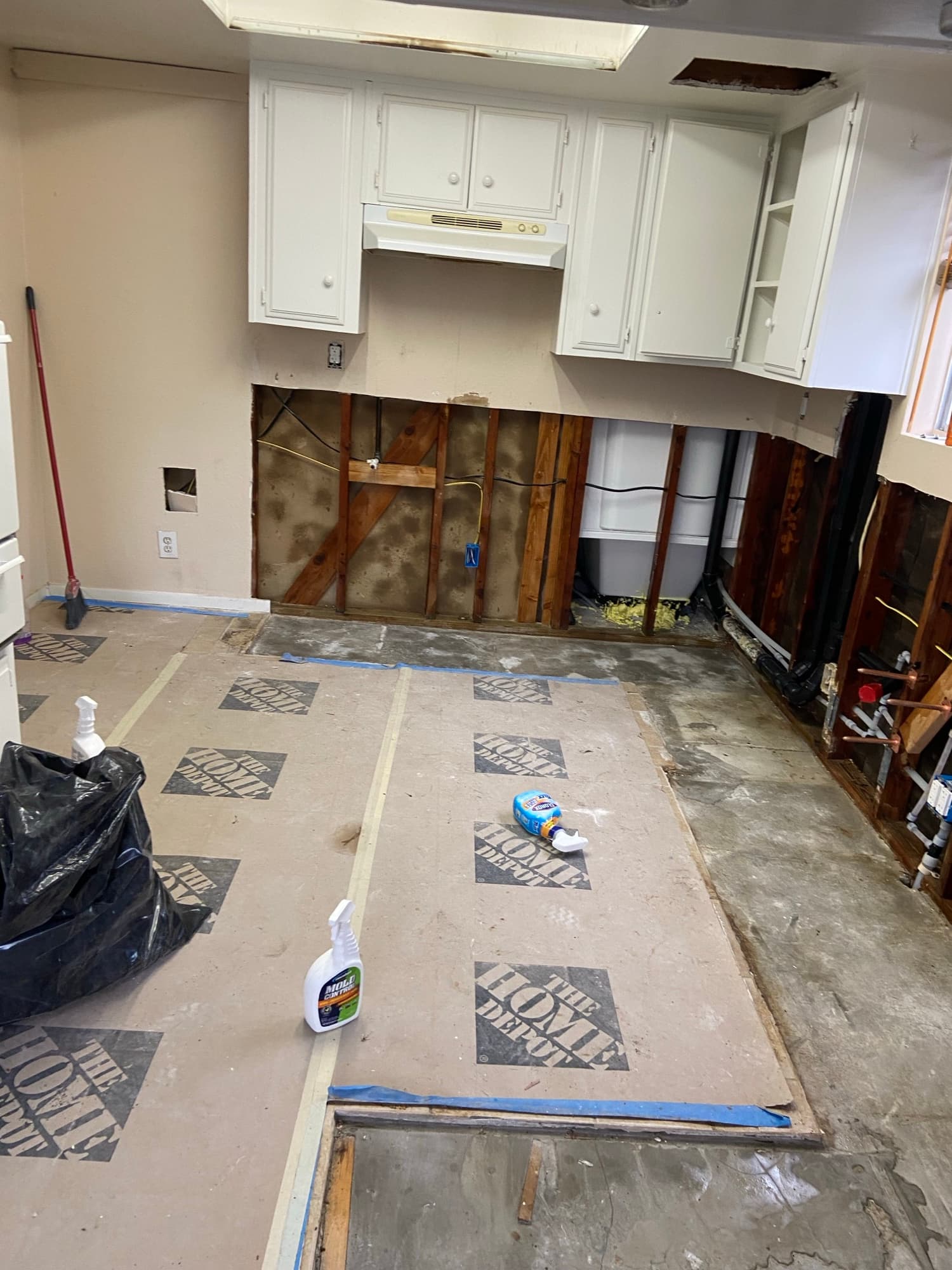 Plumbing lines run through open ceiling framing near kitchen cabinetry, Orange County, CA