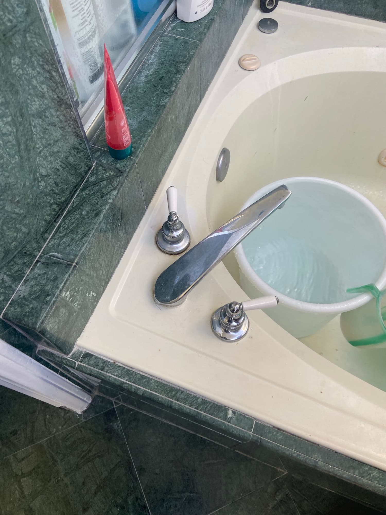 Chrome tub faucet with cross handles filling a vintage green marble tub, Orange County, CA