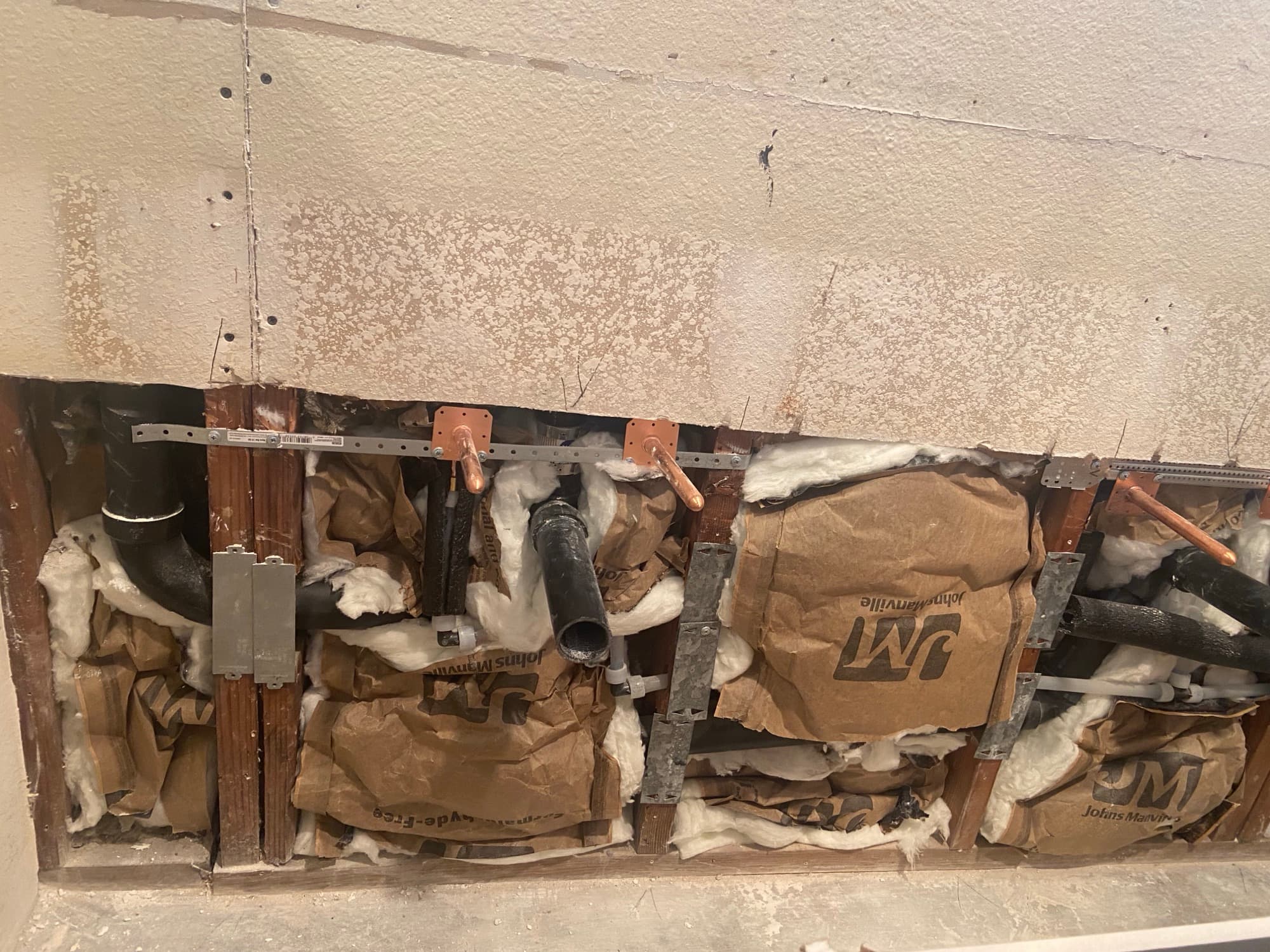 Row of copper supply stub-outs and ABS drain lines in a wall cavity, Orange County, CA