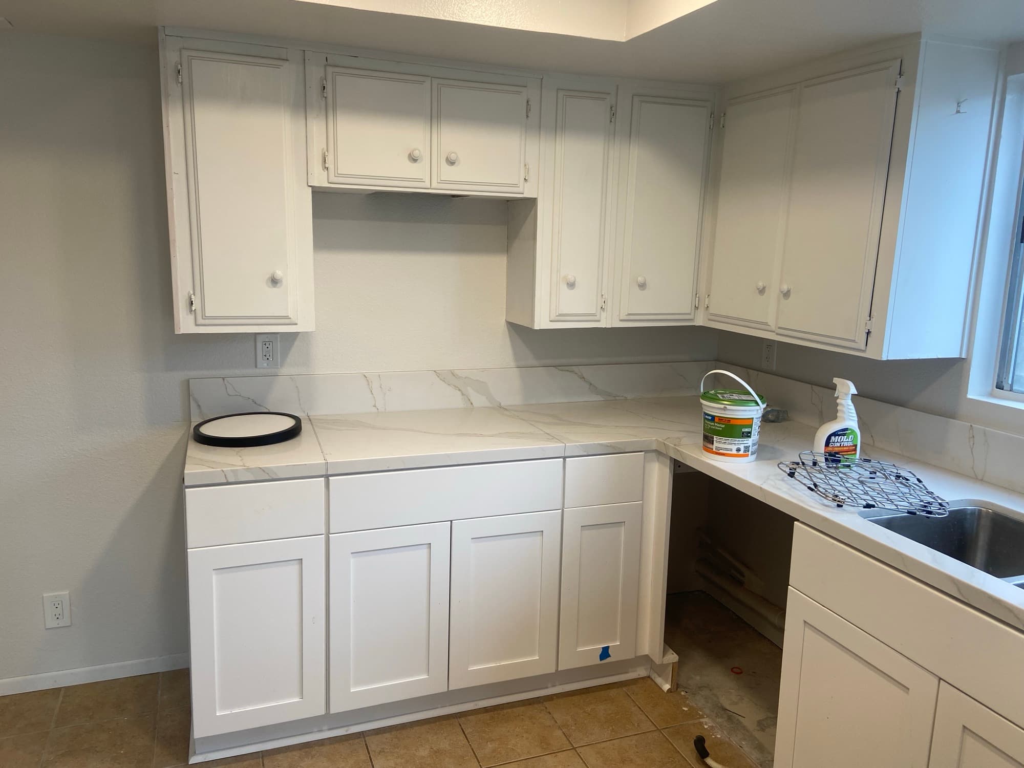 Finished kitchen countertop and cabinets with plumbing access open below the sink, Orange County, CA