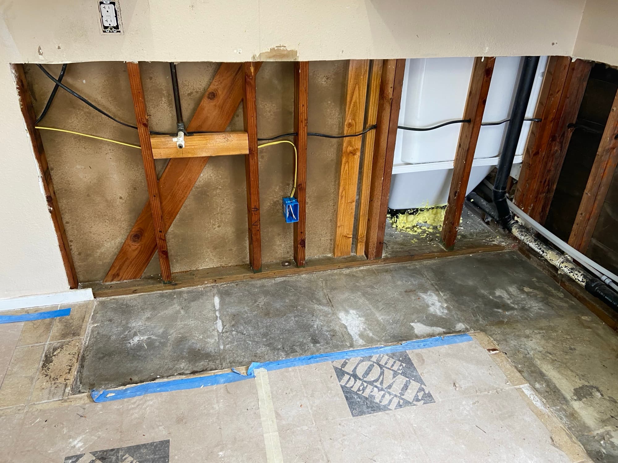 Wall opened to the studs with a shutoff valve and bathtub visible behind, Orange County, CA