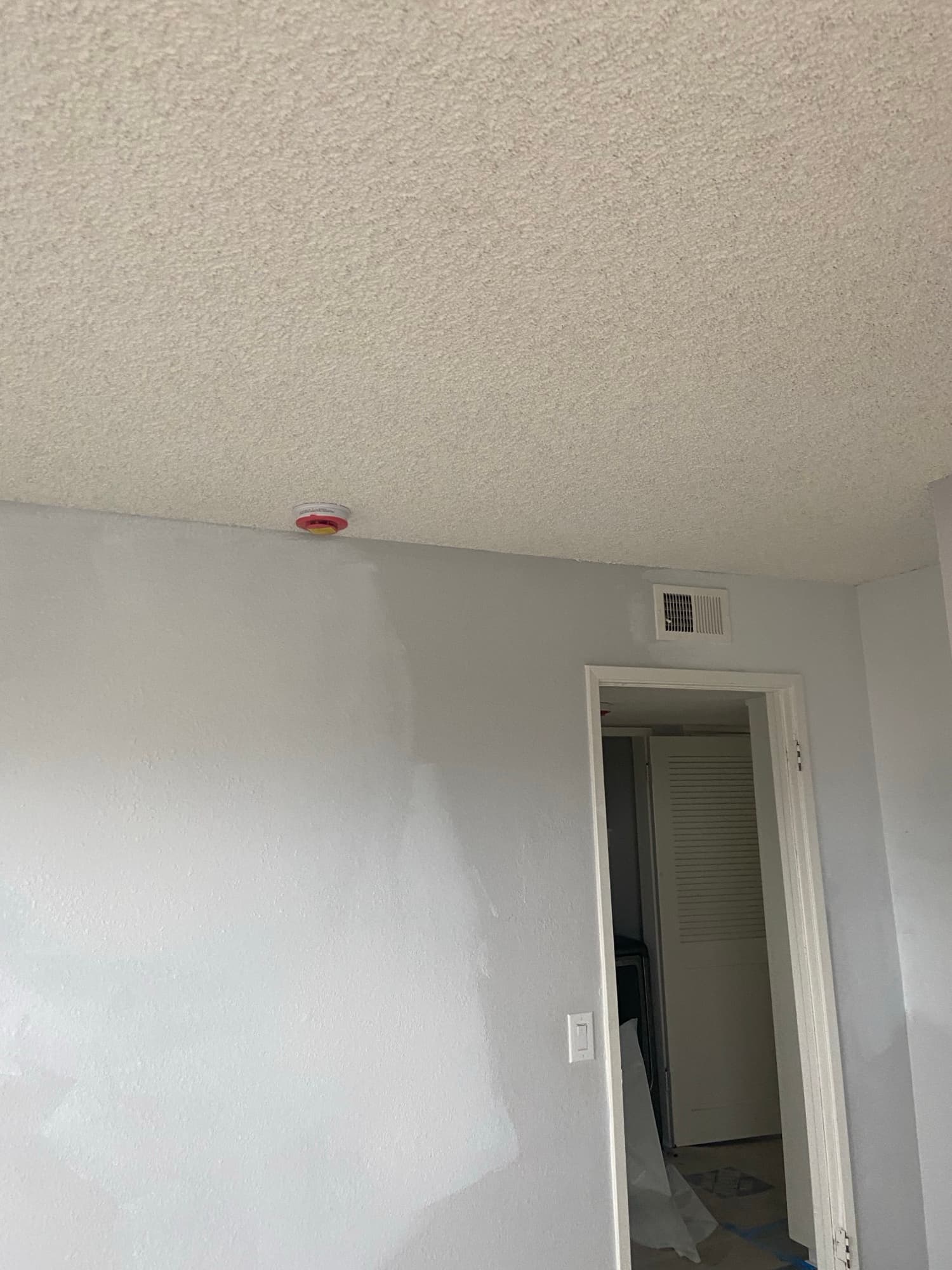 Freshly painted hallway corner with a ceiling air vent after plumbing wall repairs, Orange County, CA