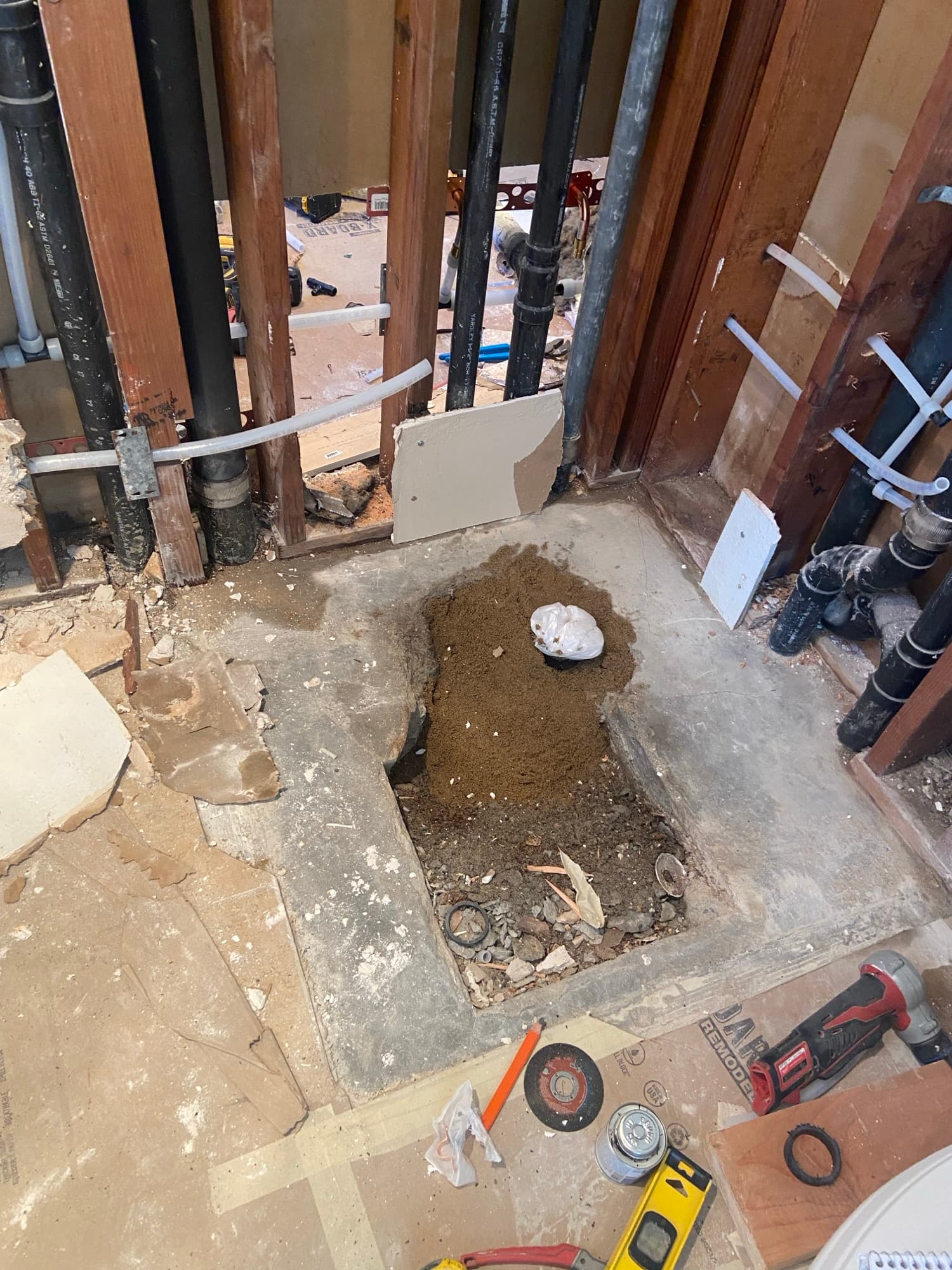 Excavated subfloor opening with pipe fittings and tools during a plumbing repair, Orange County