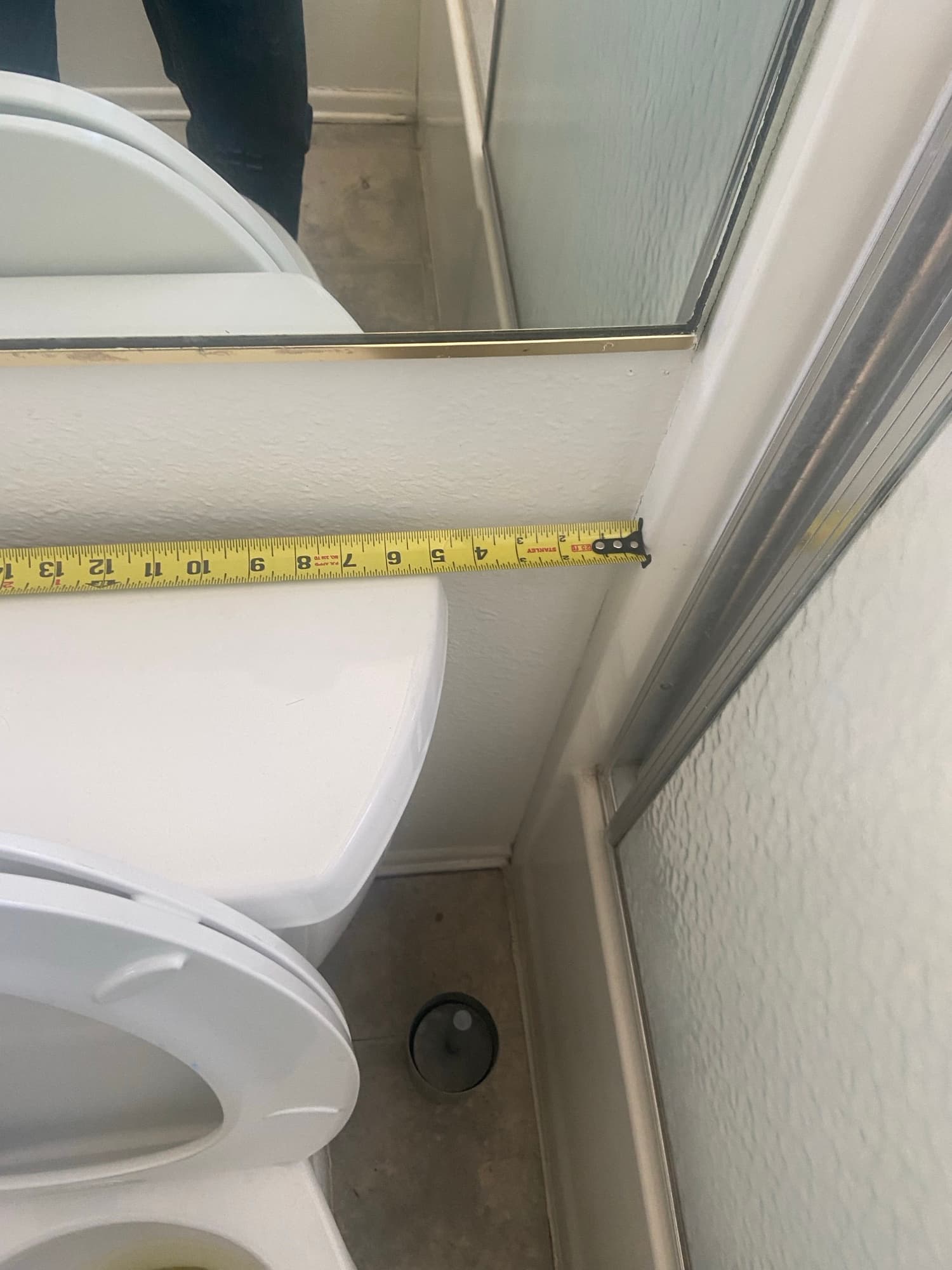 Tape measure checking clearance beside two toilets staged in a bathroom remodel, Orange County, CA