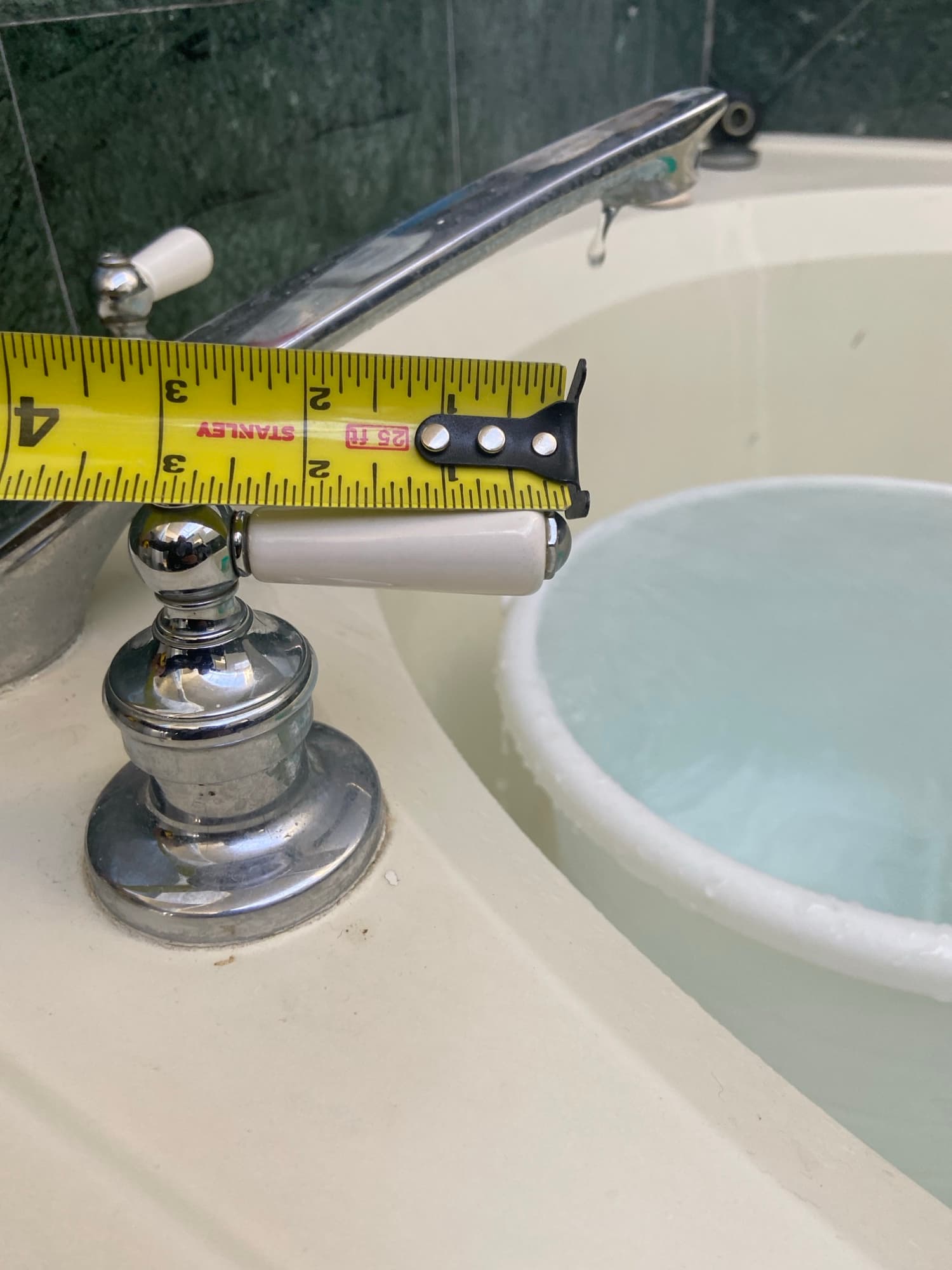 Tape measure checking spout height on a dripping chrome tub faucet, Orange County, CA