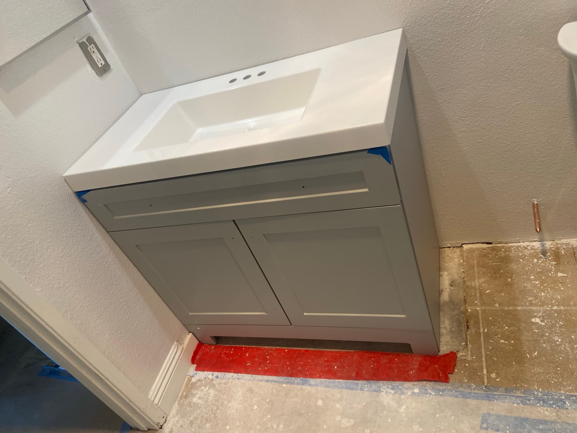 Bathroom vanity with a white sink top installed beside an electrical outlet, Orange County, CA